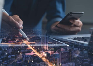 Person working on a tablet and laptop and phone.